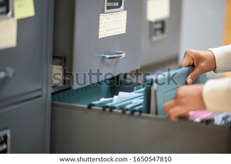 Working women searching for documents in filing cabinets at the office