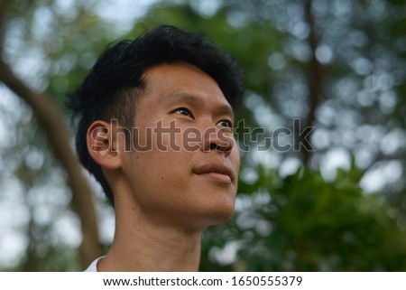 A portrait of Asian Thai man's face. He gives a 45 degree angle to the camera, eyes looks up  into the sky Royalty-Free Stock Photo #1650555379