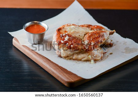 Filet grilled chicken with spices and garlic served on a wooden cutting board on dark wooden table. Food photography concept.