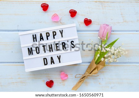 Top view lightbox with a sign HAPPY MOTHER'S DAY, rose petals and bouquet on a wooden background. Mother's day concept