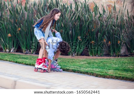 A girl training her friend boy roller skate in the park. Children, lifestyleand activity concept
