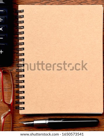 close up of notebook with pen, glasses and calculator on wooden background