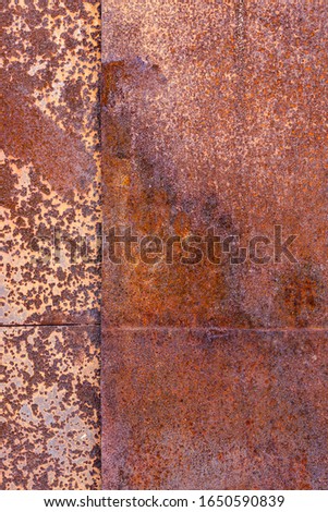 two sheets of rusty metal welded together lie on each other.