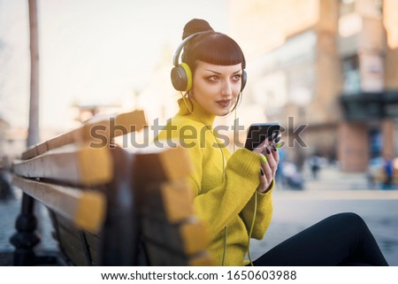 Urban goth girl listening to her music over her big headphones, street in a city surroundings Royalty-Free Stock Photo #1650603988