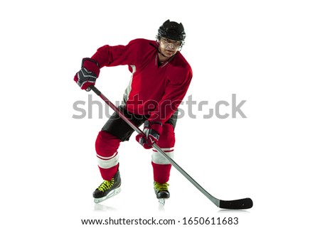 Scoring a goal. Male hockey player with the stick on ice court and white background. Sportsman wearing equipment and helmet practicing. Concept of sport, healthy lifestyle, motion, movement, action.