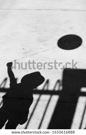 Shadow of a little boy with a balloon on the asphalt in black and white. child is alone with the balloon