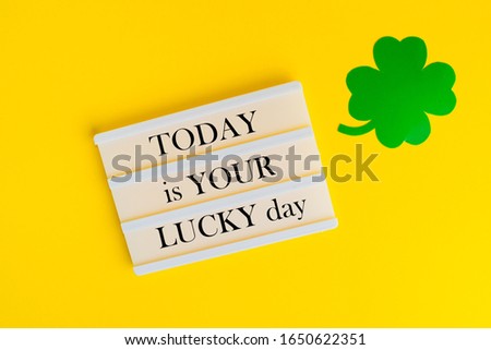 Text on lightbox TODAY IS YOUR LUCKY DAY. St. Patrick's Day concept. Shamrocks on yellow background. Paddy's Day.