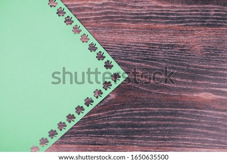 Background for St. Patrick's day. Green cardboard with a stencil of clover leaves. Space for text