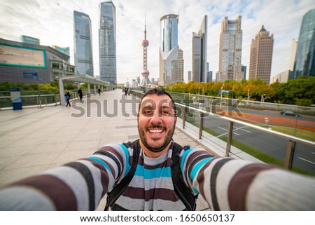 Happy tourist man take selfie with Shanghai skyline, handsome smiling man traveling in China