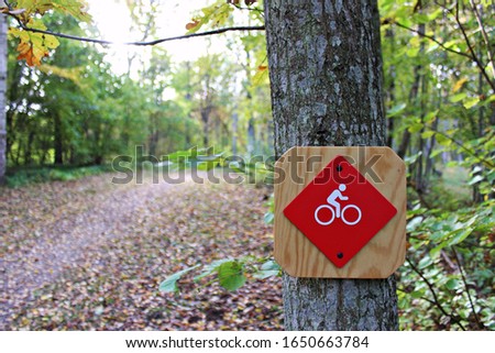 Sign with a bike on in a forrest to show the path. bicycle sign for directions.