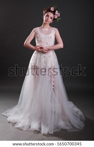 Beautiful brunette girl in the image of a bride with flowers in her hair. Beauty face. Wedding image. Picture taken in the studio on a black background.
