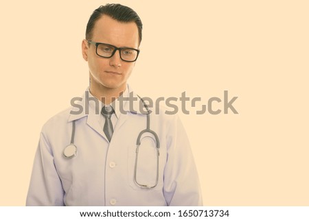 Studio shot of young sad man doctor thinking while looking down