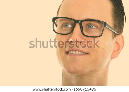 Close up of young happy man smiling and thinking while wearing eyeglasses