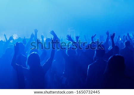 Silhouette of people with raised hands on concer. Crowd on music show