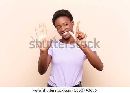 young pretty black womansmiling and looking friendly, showing number seven or seventh with hand forward, counting down