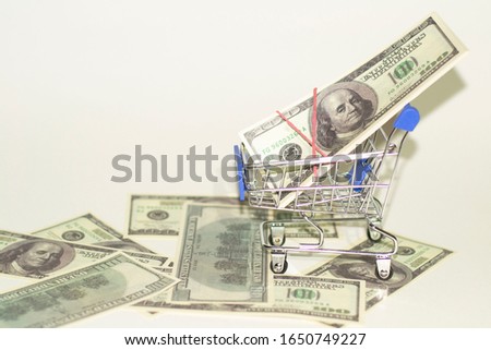 top view of dollars in a basket trolley and on the floor. whitebackground