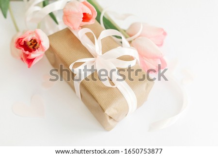 Pink tulips with ribbon and gift box on white background. Stylish soft image of spring flowers. Happy womens day. Greeting card mockup. Happy Mothers day.  Hello spring