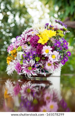 colorful winter flower in the vase on the table with the reflection