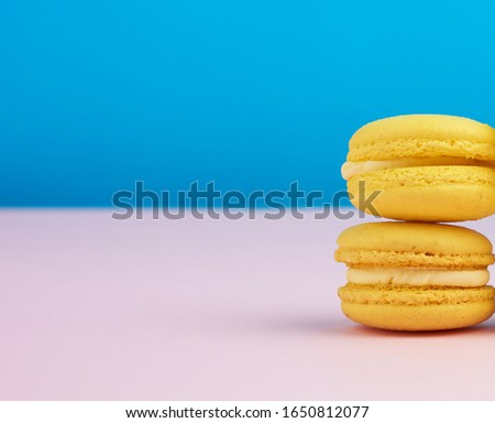 stack of baked round yellow lemon macarons on a blue-pink background,  delicious and delicious French dessert