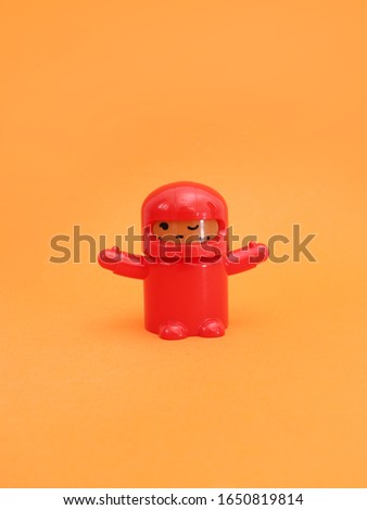 Mini cute cartoon figure toy with red motorcycle helmet on orange background