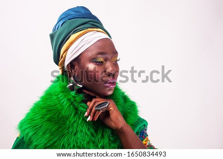Studio fashion portrait of young African ethnicity woman with ethnic head wrap, white background.