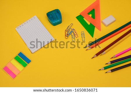 A set of stationery. Colored pencils, sharpener, eraser, ruler, notepad, paper clips and stickers on a yellow background, space for text. Flat lay. school supplies. office