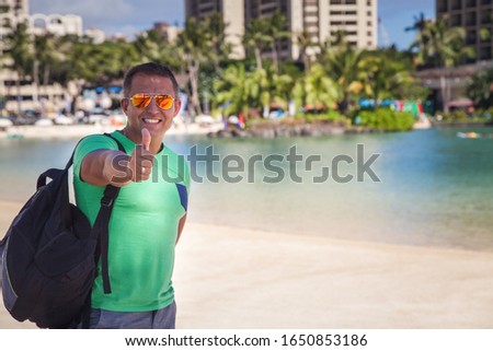 Happy man shows gesture cool, thumb up expressing positivity. Honolulu City, Oahu, Hawaii summer travel.