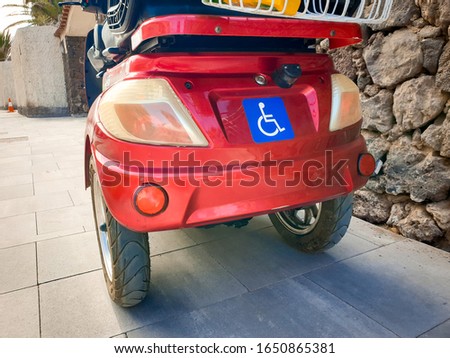 Closeup photo of dasbled person sign on the electric wheelchair with three wheels