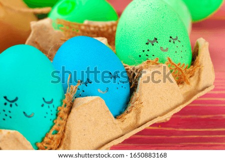 Blue and green colored Easter eggs with drawn funny faces. Creative photo