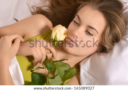 Beautiful young girl lying in bed with flowers bouquet