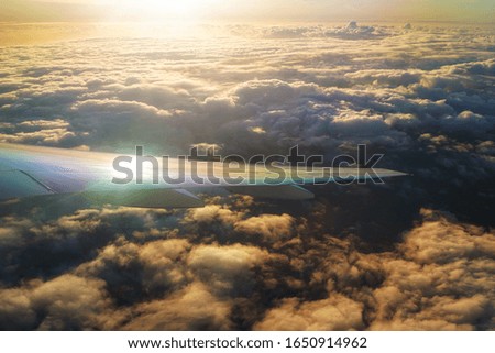 Photo shows aircraft wing with sun rays and dramatic cloud.