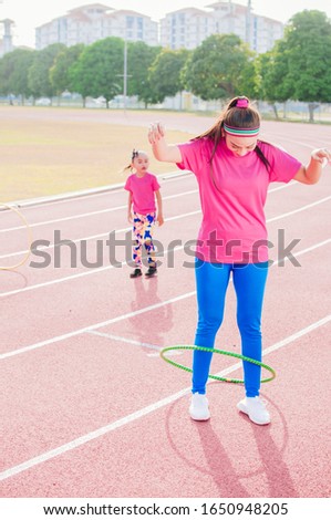 Young lady and kids practicing with hula hoops and have fun