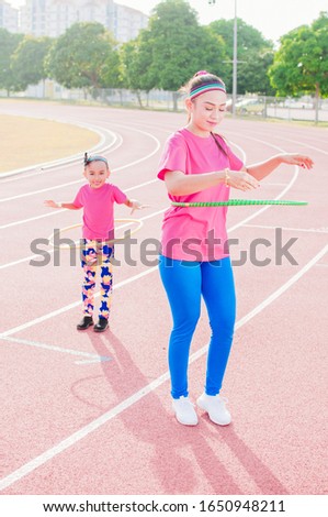 Young lady and kids practicing with hula hoops and have fun