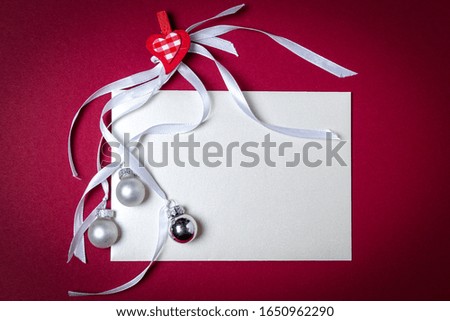 Greeting card with ribbon and Christmas balls on red background. Top view with free space for copy text