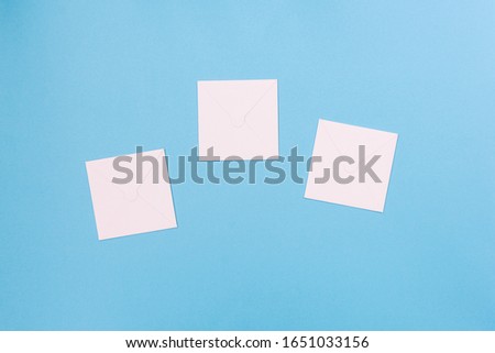 Three white sheets of paper on a blue background. Empty cardboard envelopes for text.