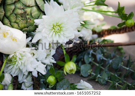 Top view of bridal bouquet with white,pink and rose flowers with wedding rings on it lying on grass in summer wedding day. Wedding decor. Idea for groom and bride rings picture.