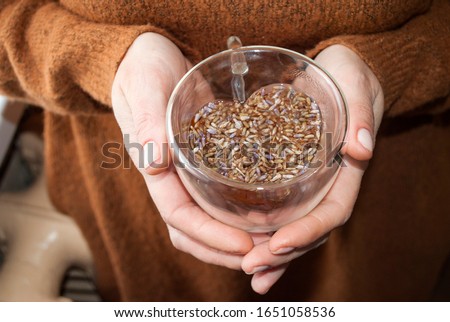 Glass cup in the shape of a heart and double glass in female hands. Lavender Tea. Healing decoction of lavender flowers.