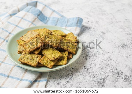 Healthy snack crispy salty square crackers with fragrant herbs and seeds in a plate on a white textured background. Royalty-Free Stock Photo #1651069672
