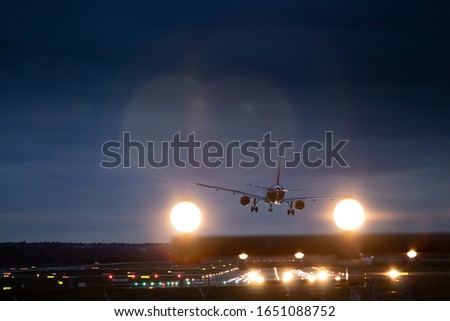 Airplane landing in the evening at the airport of Hamburg. Picture taken perfectly from behind the landing strip with the guiding lights