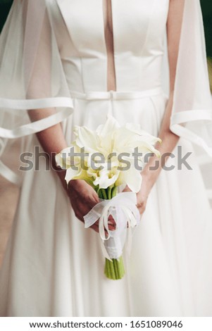 the bride holds in her hand a bouquet of callas