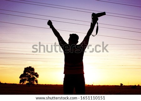 silhouette of young man photographer, taking pictures of landscape at sunset