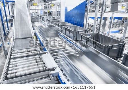 Modern conveyor system with boxes in motion, shallow depth of field. Royalty-Free Stock Photo #1651117651