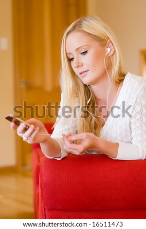 A young attractive woman sitting on sofa listening to music