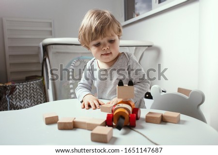 Beautiful toddler play with a wodden toys at home. Child play at the table in the baby room.  Funny baby. Lifestyle