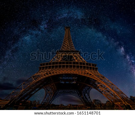 The Eiffel Tower at night under the Milky Way galaxy in Paris, France. Low angle wide perspective view