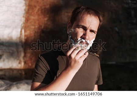 Man shaves his face at the river's edge