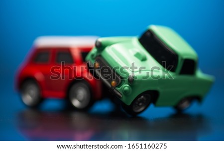 Close up shot of Traffic accident between a red and green toy cars on a blue backround.