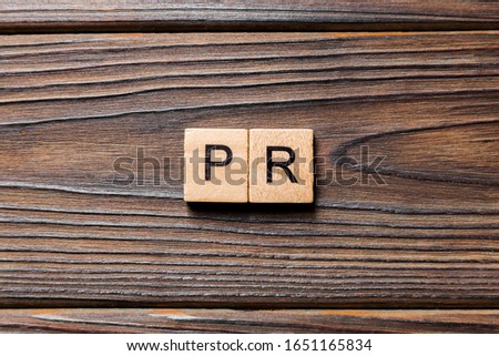 pr word written on wood block. public relation text on table, concept.