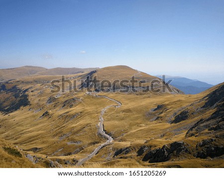 Alpine landscape with winding road and hiking trail in mountains