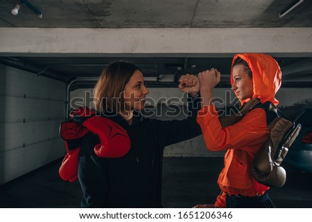 Profile pricture of two happy women boxer friends smiling and making high five before workout
